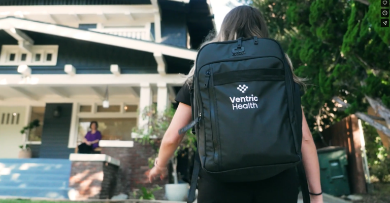 Healthcare professional wearing a Ventric Health backpack, visiting a patient's home to perform heart failure diagnosis in a home setting.