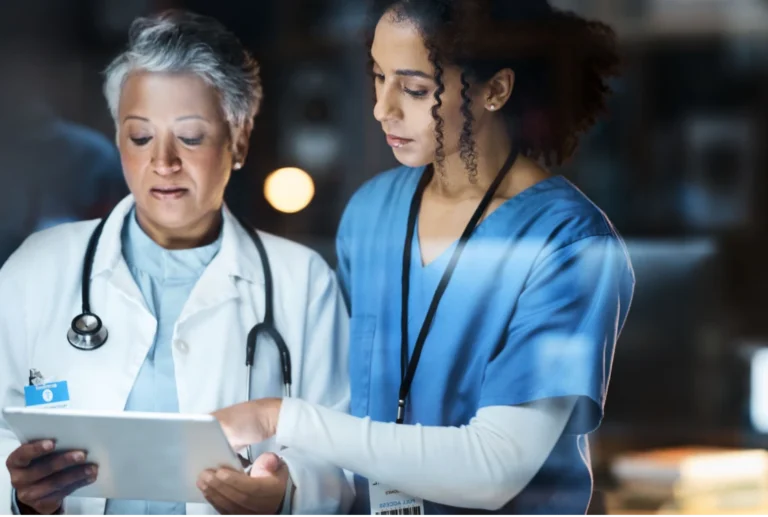 Link to the Who We Serve page for healthcare systems, hospitals, and medical groups. Medical professionals collaborate using a tablet.