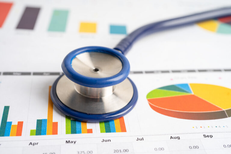 Stethoscope on spreadsheet paper depicting charts and graphs to illustrate the cost impact of value-based care.
